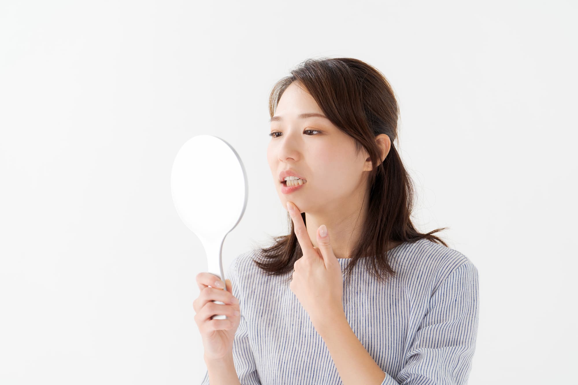 すきっ歯が気になり鏡で歯を見る女性