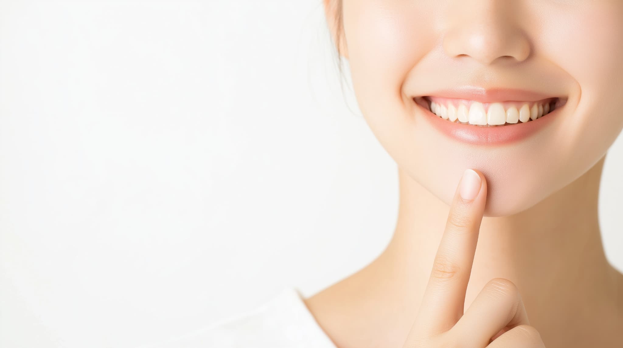 きれいな歯並びの前歯を指さす女性