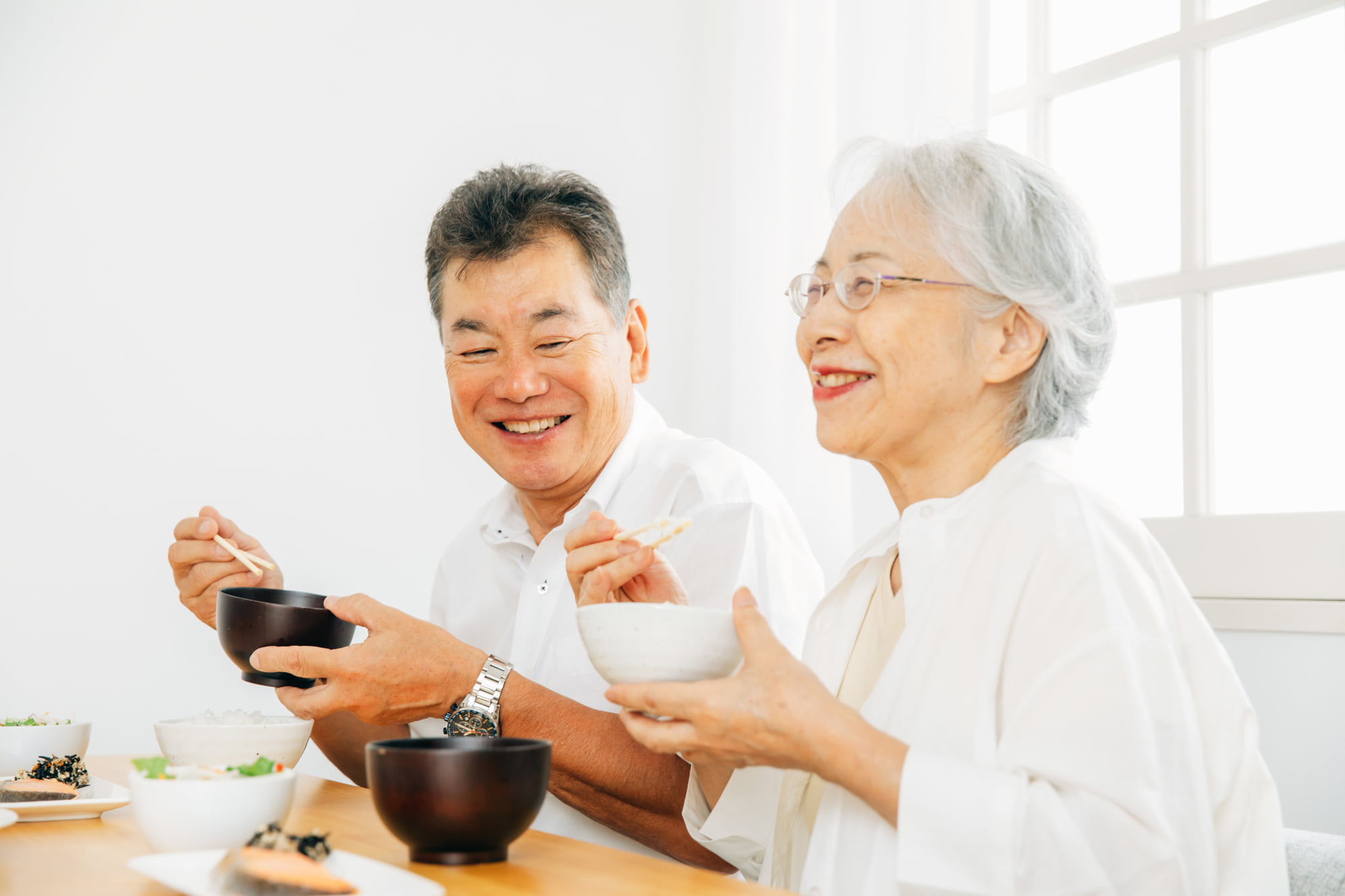 適切な手入れをした入れ歯で快適に食事をしているシニア女性