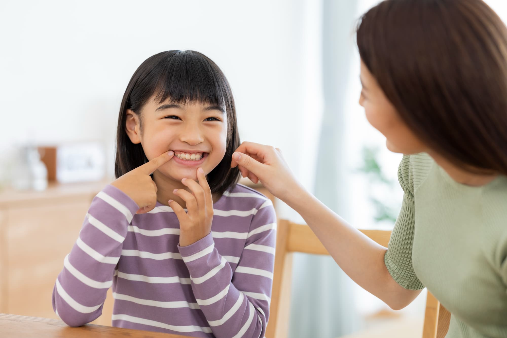 出っ歯が治って嬉しそうに前歯を指さす女の子