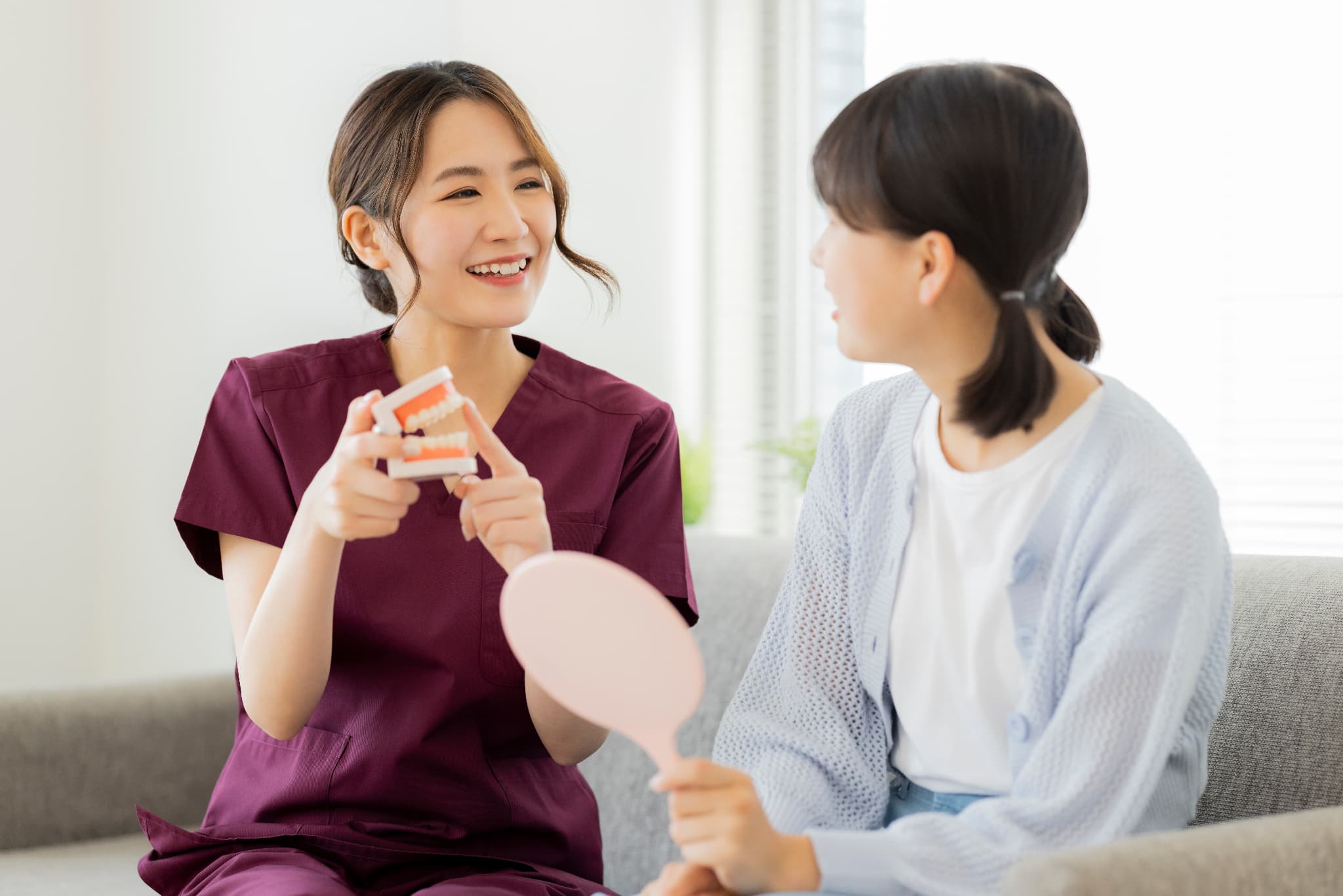 出っ歯について歯医者で相談する女の子と説明する歯科衛生士