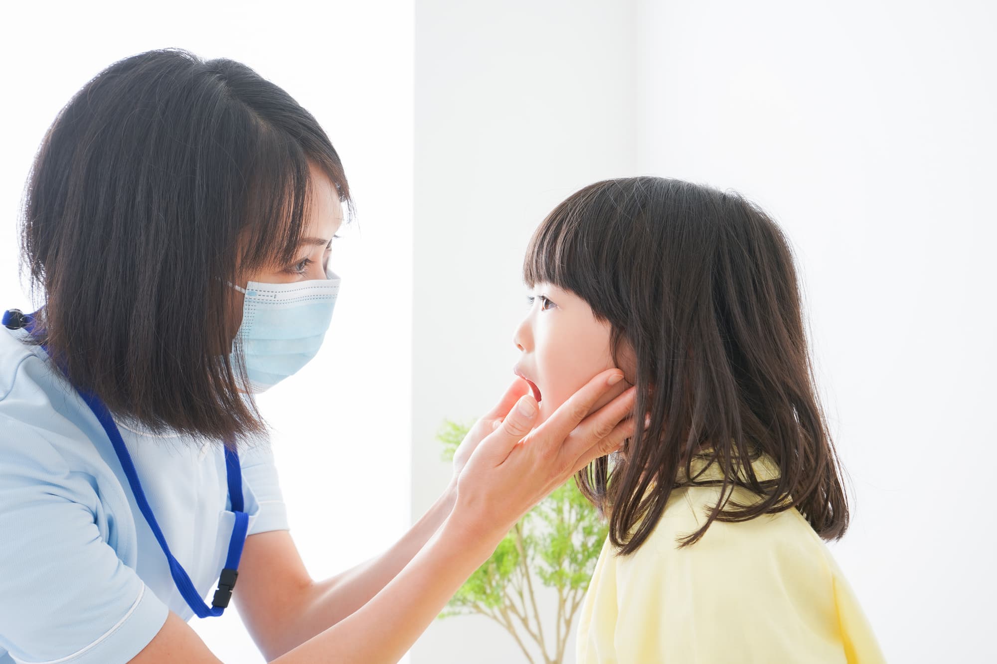 子供の歯並びをチェックする歯科医師